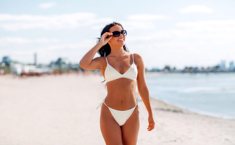 A woman wearing sunglasses and a white bikini at the beach